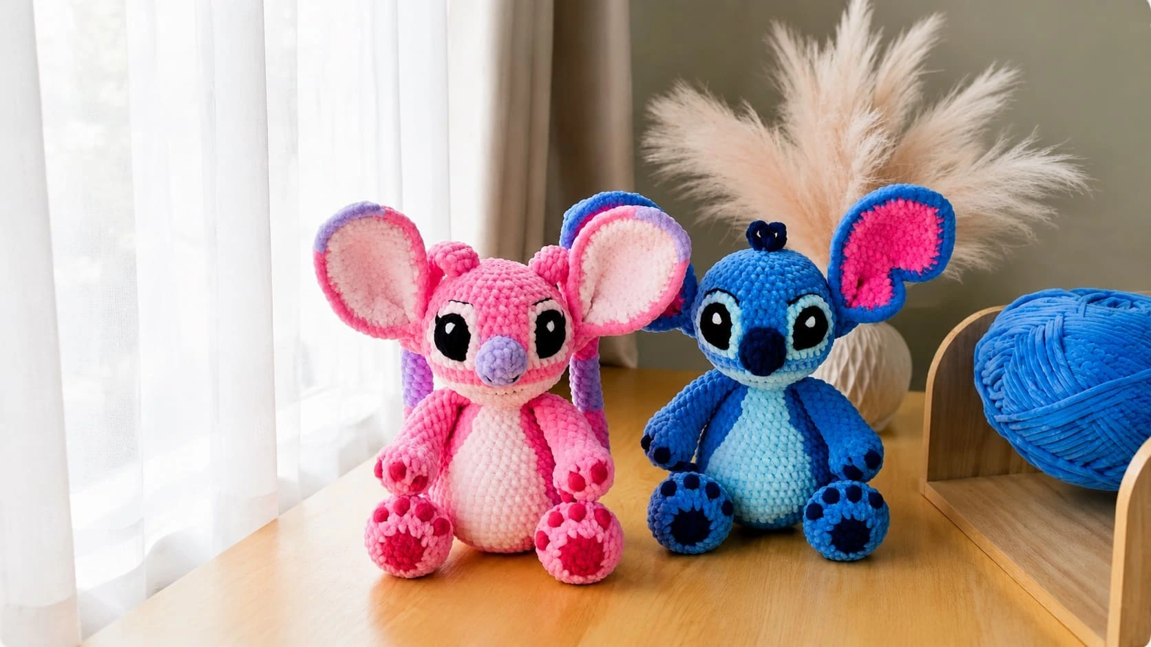 Finished pink Angel and blue Stitch crochet plushes sitting side by side on a wooden shelf
